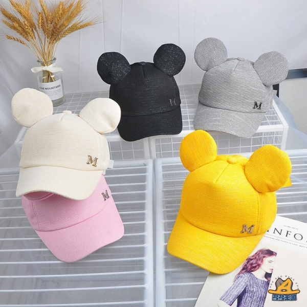 Gorro de verano infantil de moda en varios colores sobre una mesa con un jarrón