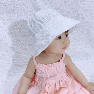 Niña asiática sentada con vestido rosa y boina blanca mirando a la derecha