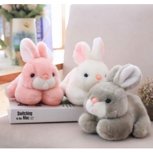 Simpático conejito de peluche para niñas, varios colores sobre una mesa con un libro