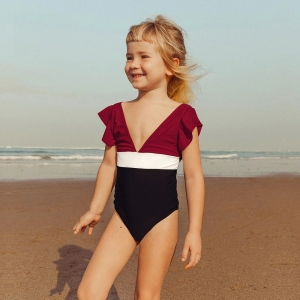 Chica rubia sonriente en la playa con bañador de una pieza