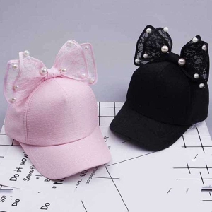 Gorra de niña con pajarita negra y rosa sobre la mesa