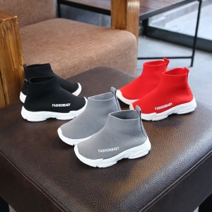 Zapatillas deportivas casuales de caña alta en rojo, negro y gris para niñas sobre una silla en una casa