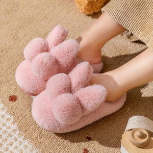 Suaves zapatillas de conejo de felpa rosa, usadas por un niño