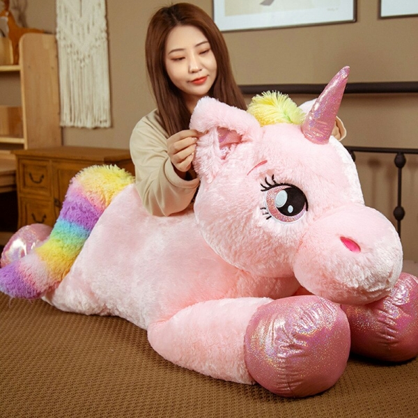 Peluche gigante de unicornio para niñas sobre la alfombra de una casa