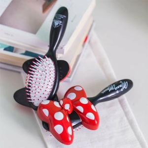 Cepillo para el pelo con lazo rojo de Minnie para una niña sobre una mesa con un libro
