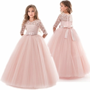 Una joven lleva un vestido de fiesta rosa de encaje y tul con mangas tres cuartos y un lazo delante y otro detrás. La foto muestra a la niña por delante y por detrás para mostrar ambos lados del vestido.