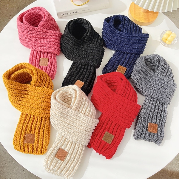 siete pañuelos anudados y dispuestos sobre una mesa blanca redonda, los colores son rosa, negro, azul oscuro, amarillo, blanco, rojo y gris sobre una mesa blanca