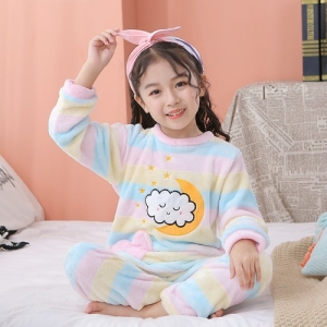 Pijama de vellón con motivos de luna y nubes para niñas que lleva una niña en una casa