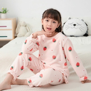 Bonito pijama rosa de forro polar para niñas llevado por una niña en la cama de una casa