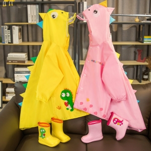 Mackintoshes para niñas en rosa y amarillo con un dragón verde sobre ellos, en un sofá y delante de una estantería