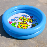 Piscina infantil hinchable azul con motivos de animales de colores, colocada en el suelo