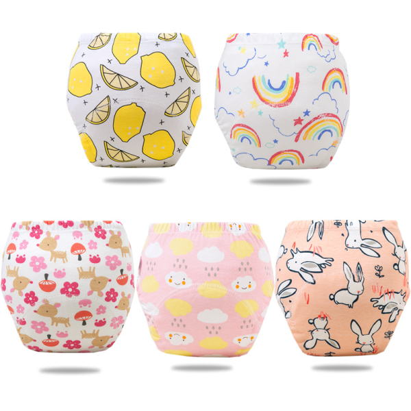 Sobre fondo blanco, 5 pantalones entrenadores impermeables para niñas: uno blanco con motivos de limones, uno blanco con motivos de arco iris, uno blanco con ciervos beige y flores rosas, uno rosa con nubes sonrientes amarillas y blancas y gotas de lluvia y uno melocotón con conejos blancos