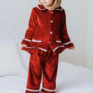 Niña rubia de pie, con pijama navideño de terciopelo rojo