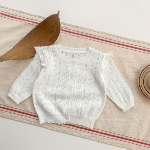 Chaleco blanco calado con volantes sobre un tejido beige y rojo