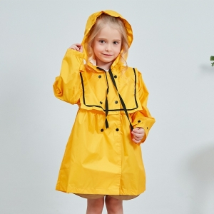 Niña rubia sonriente, de pie, con un impermeable amarillo con capucha