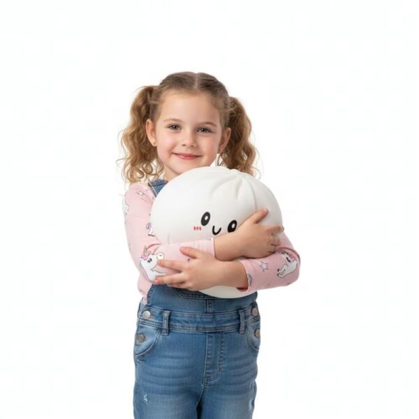IMG_squishy_dumpling_geant_anti_stress_pour_fille.jpg Jeune fille debout avec des couettes, portant un jean et un t-shirt rose, qui tient dans ses bras un squishy dumpling blanc.